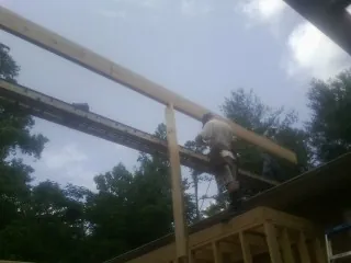 Carpenter setting a ridge beam over a new addition frame — Ice Dam Removal by Roofing Brothers in Milo