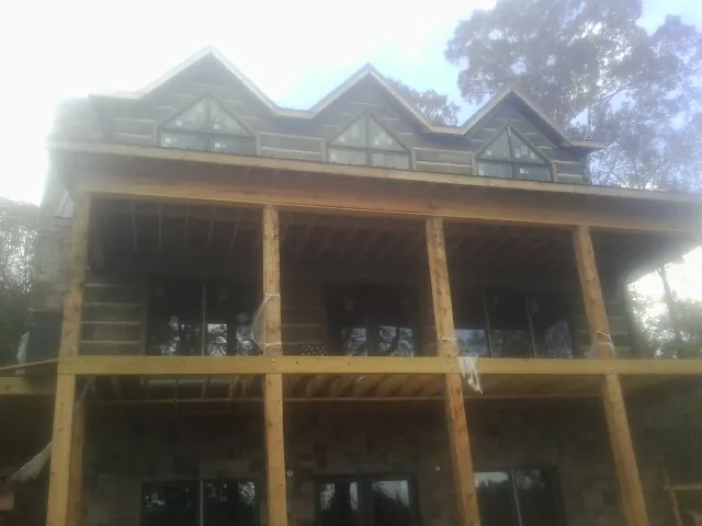 Dormers and porch framing on a large log home under construction — Roof Coating work by our crew in Milo