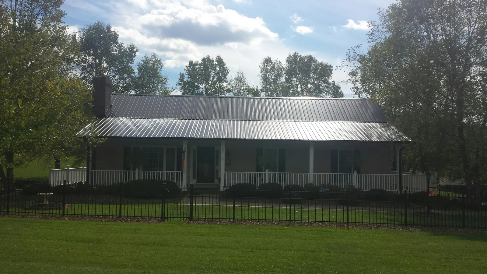 Gray metal roof on a brick ranch with a full width front porch — Gutter Guard Installation work by our crew in Milo