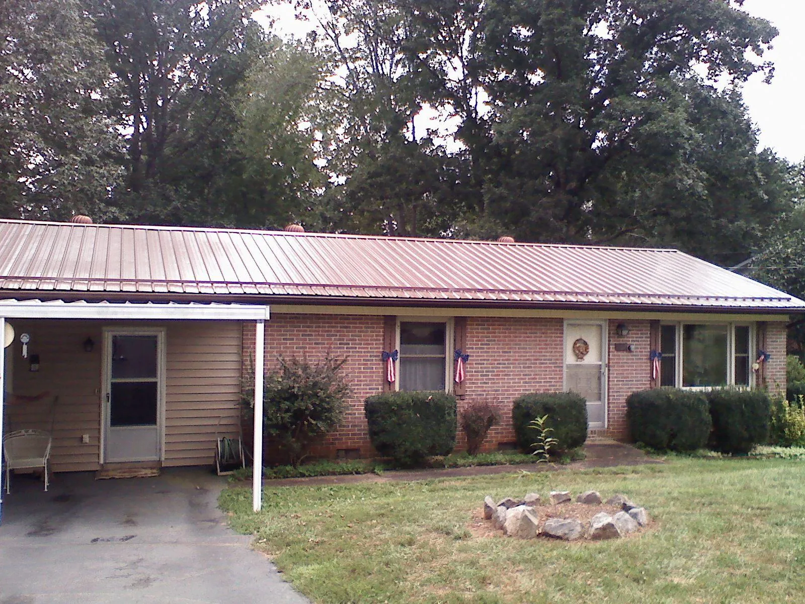 Bronze metal roof and carport on a brick ranch home — Roof Repair work by our crew in Milo