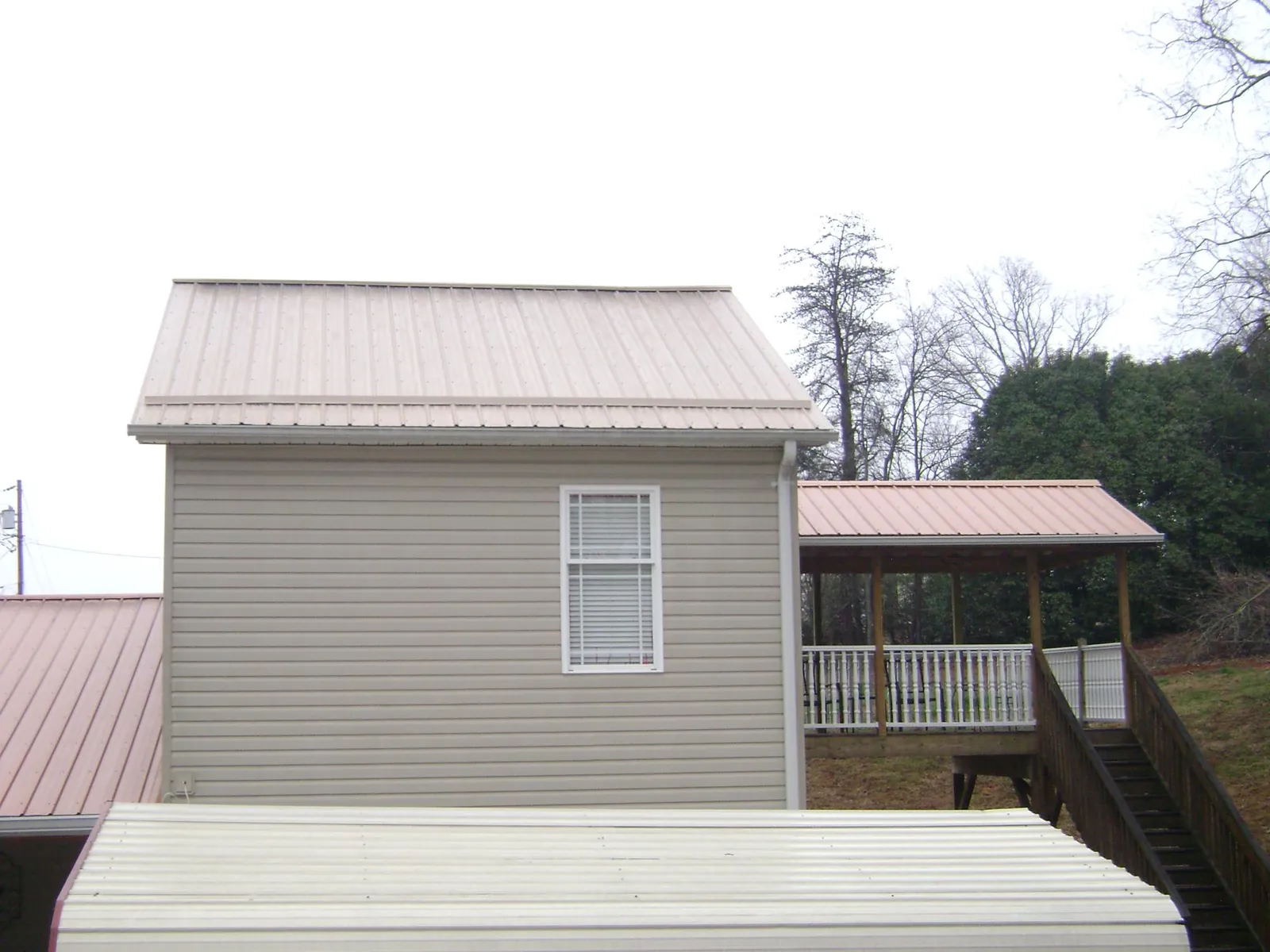 Tan metal roofs on a two story addition and attached porch, from a Roof Replacement job in Milo