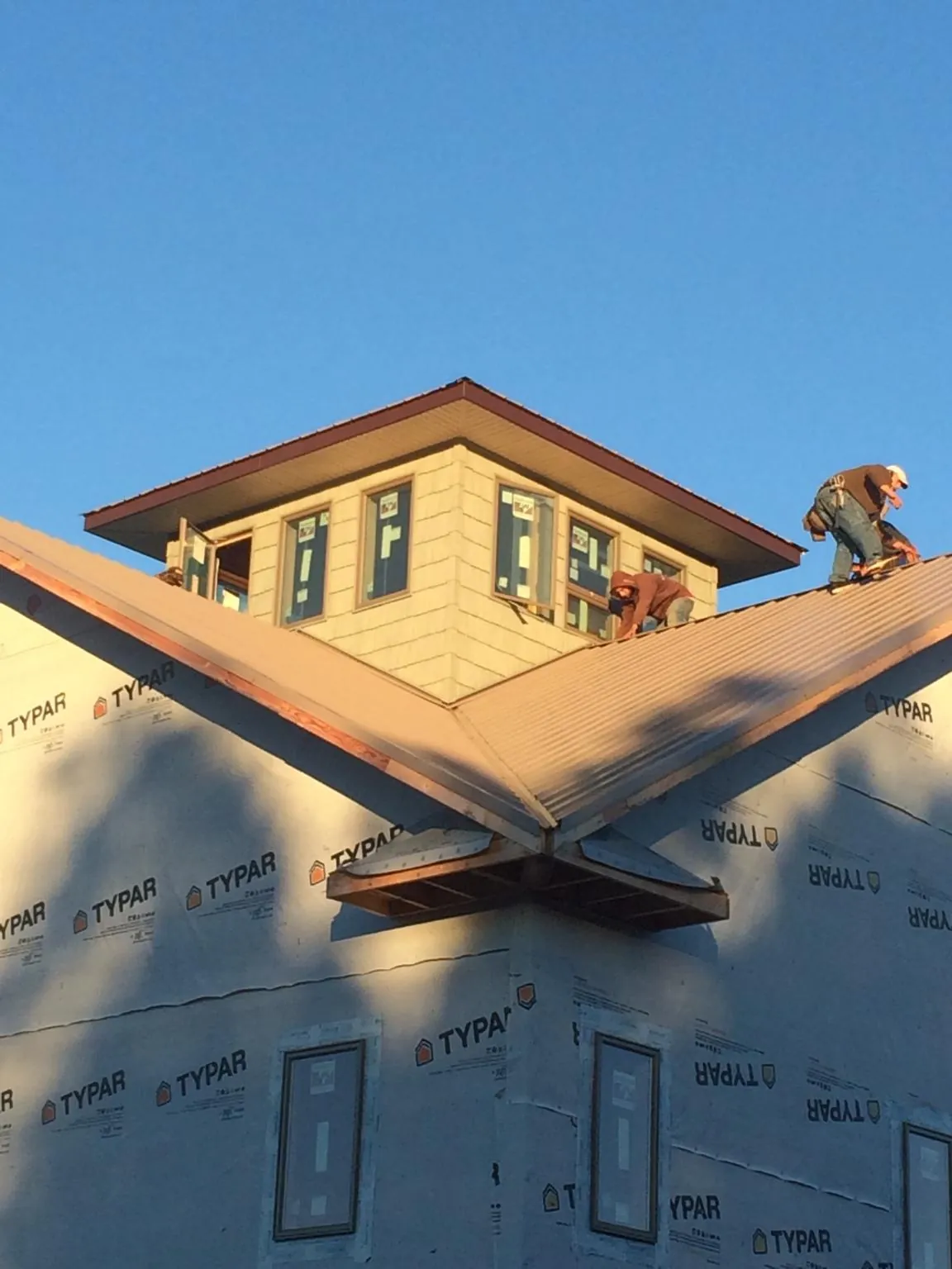 Roofers working around a rooftop cupola on a new metal roof at sunset — Roof Waterproofing in Milo by Roofing Brothers